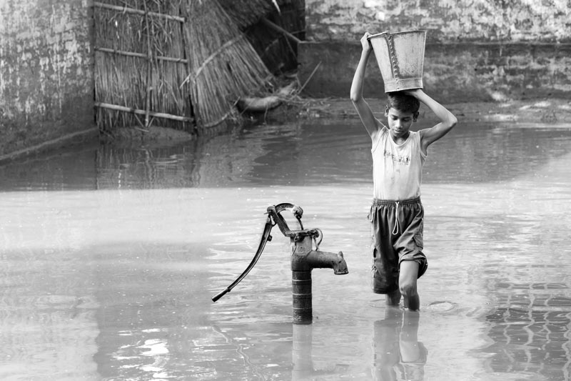 Children and Water - A boy carrying a bucket of 'safe' water amidst floods in West Champaran district, Bihar